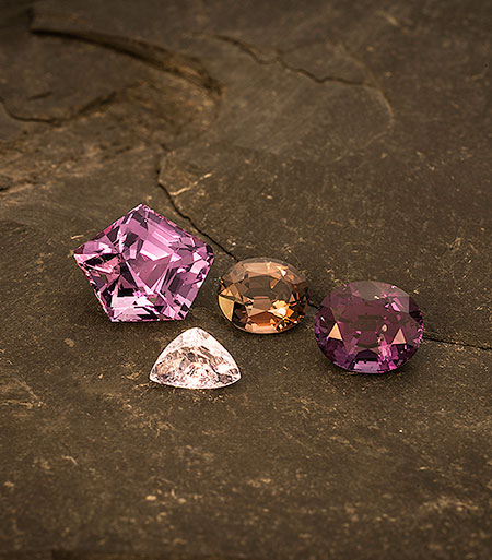 Fab four. From left, 8.50-carat purple pentagon from Sri Lanka (sold), 1.66-carat lavender trillion from Burma's Mogok Stone Tract ( #7805 ), 2.35-carat brown oval from Sri Lanka (sold), and 4.28-carat mauve oval from Sri Lanka (sold). (Photo: Mia Dixon)