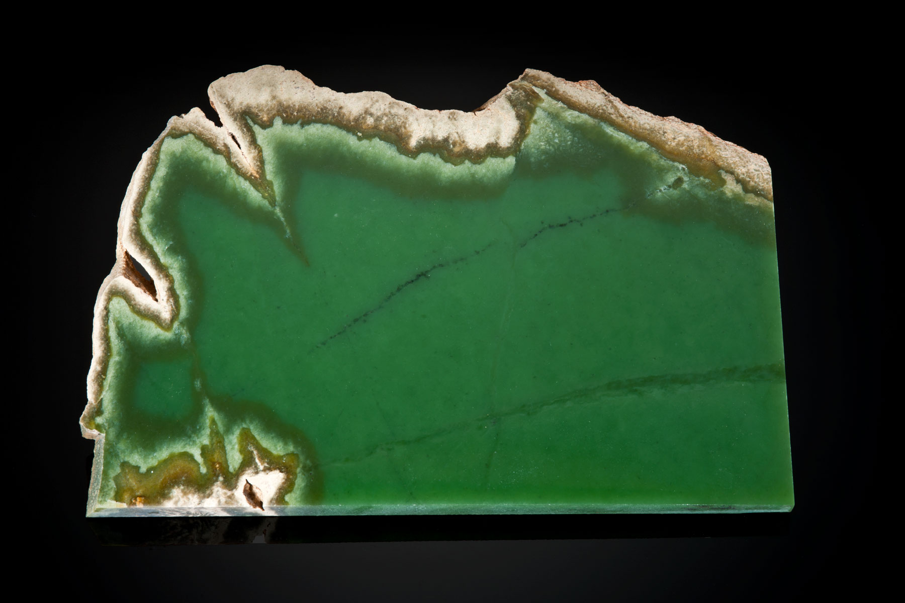 The light tan rind often hides the beautiful green jade in this 7" x 3½" x ¼" slice. Most buyers prefer the non-included, pure translucent green rather than this attractive slice and will pay dearly for such jade. (Photo: Robert Weldon)