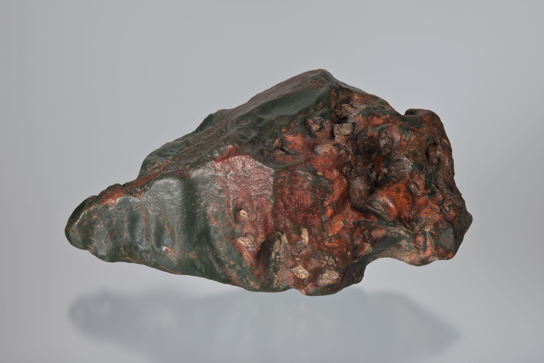 A handsome 5-lb multi-colored jade slick with an iron dark-reddish skin on the exterior of rough masses. Alteration in these boulders often proceed to about ¼ inch below the surface and shows beneath the red skin, a brownish zone of altered nephrite followed by a green opaque zone next to the nice handsome green material within the core. The piece is not "apple" or "olive" green, but rather a transition. Below are examples of "olive" green jade slicks. (Photo: Robert Weldon)