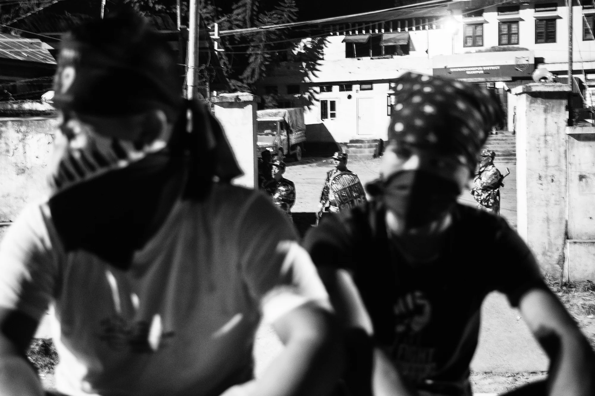 August 2016: Volunteers guard the site of an evening programme, while policemen glare from the gates of the Churachandpur Police station during a programme the volunteers organised to remember the nine young men shot dead a year earlier. Four of them had been shot exactly in front of the police station. 