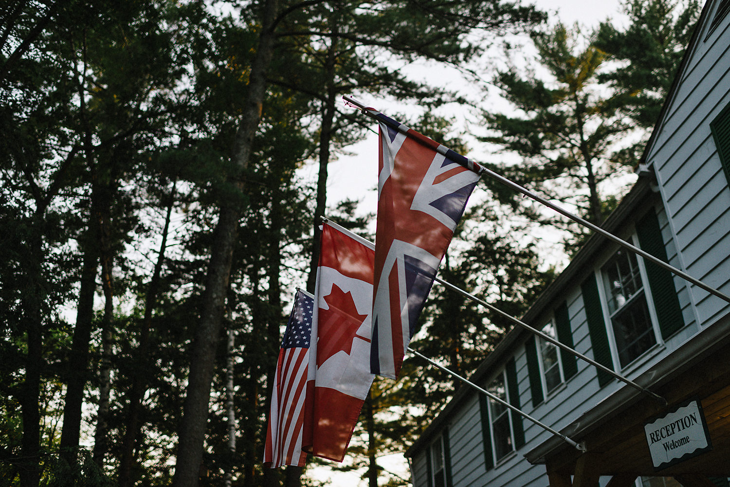 Muskoka-Cottage-Wedding-Photography-Photographer_Photojournalistic-Documentary-Wedding-Photography_Lakeside-Ceremony-Sunset-Light-on-flags.jpg