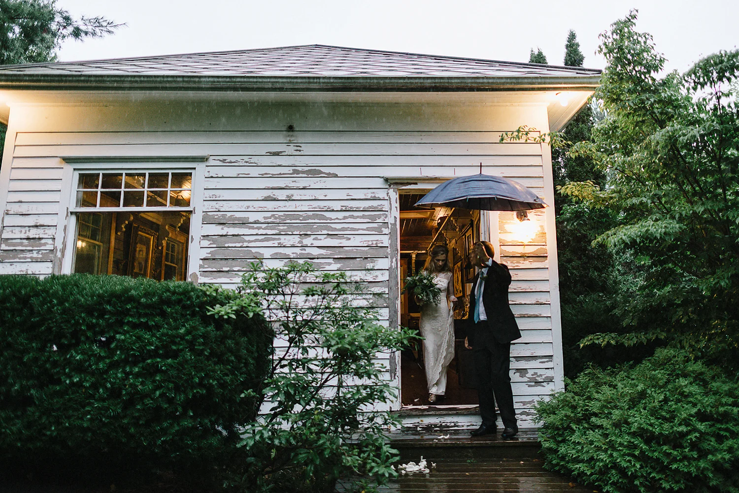 Best-Moody-Documentary-Wedding-Photography-Photojournalism-Vintage-Small-Town-Chapel-Wedding-Toronto-Ontario_Bride-Ceremony-Entrance-in-Rain-with-Umbrellas.jpg