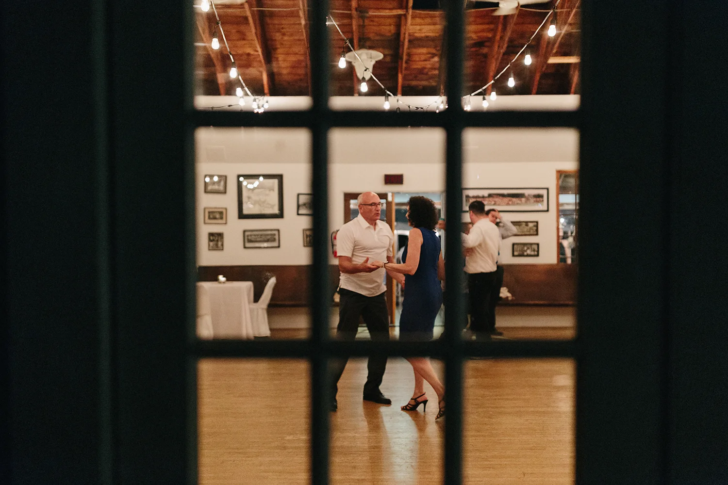 Best-Film-Wedding-Photographers-3b-photography-analog-photography-wards-island-clubhouse-junebug-weddings-vintage-venue-reception-guests-dancing-candid-moments-memories-through-window.jpg