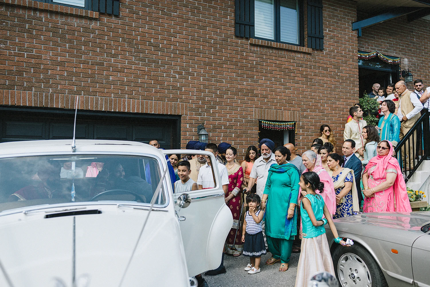 Toronto-Photojournalism-wedding-photographers-3B-Photography-Candid-Documentary-Film-Photography-Analog-Ontario-Hamilton-Port-Perry-Venue-Groom-Getting-Ready-putting-on-turban-sikh-ceremony-bride-entire-family-seeing-her-off.jpg