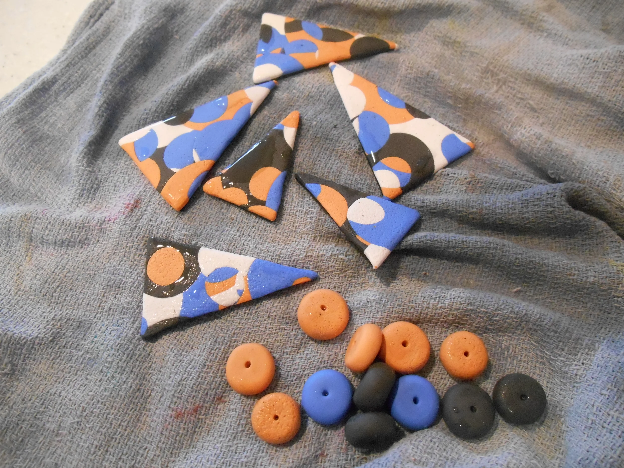Here are the fired and bathed pieces- I decided to make some textured beads as well. I think I'm going to need them for the overall length. I went with a stone gray, a periwinkle blue, some soft peach and white. I hand blended to achieve my colors.