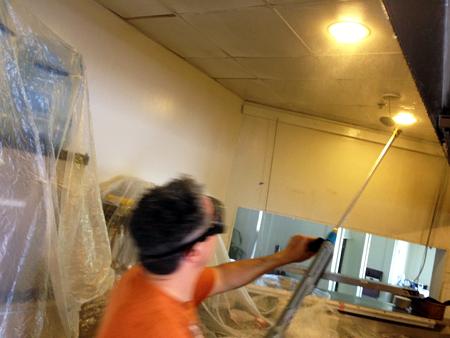 A man with glasses on cleaning light fixtures of a commercial property.