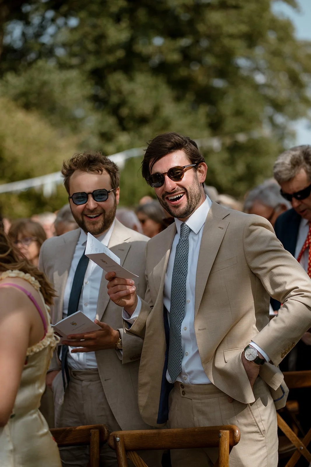 Guests smiling and reacting during an outdoor wedding ceremony in natural light