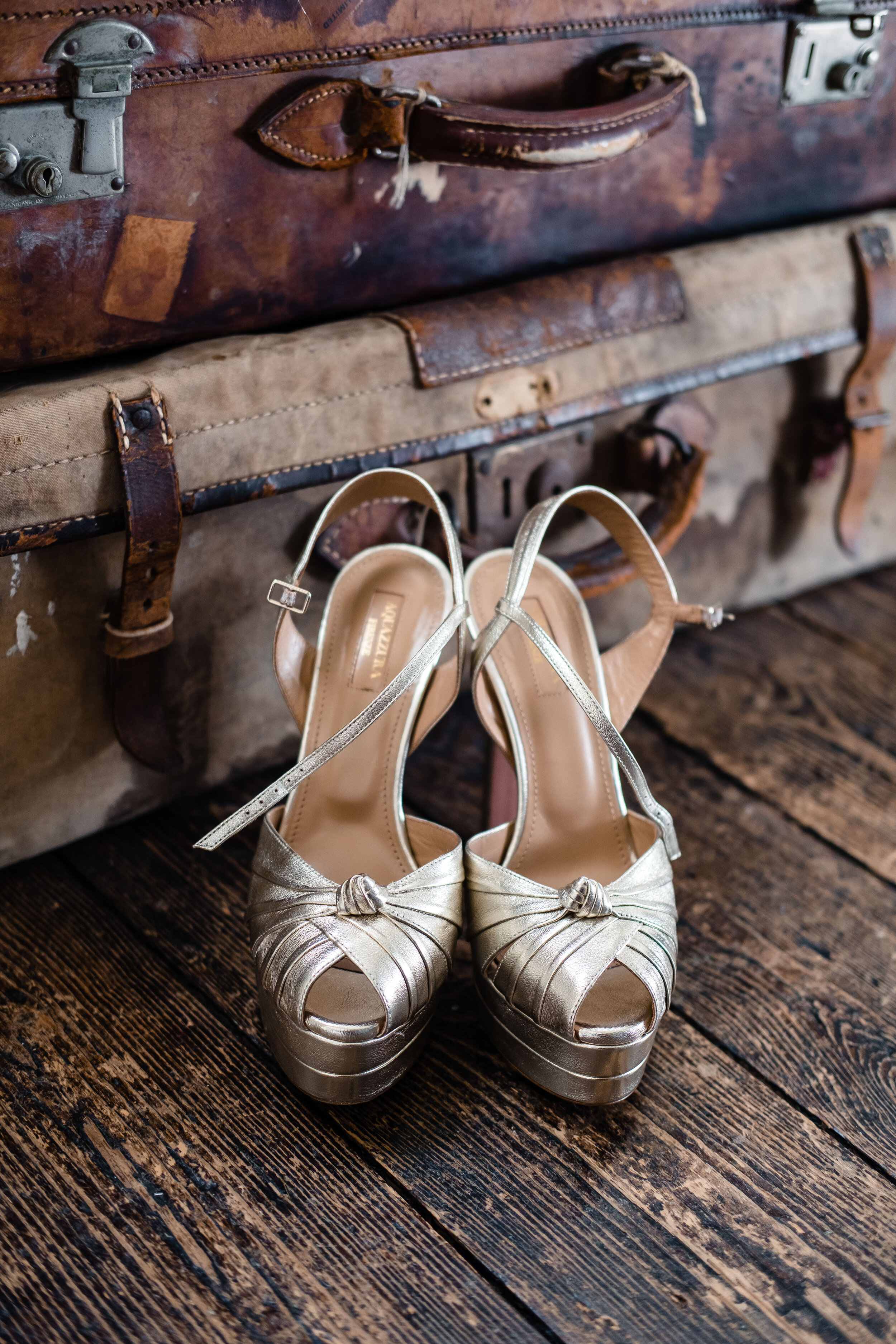 high wedged wedding shoes in gold sitting on wooden surface