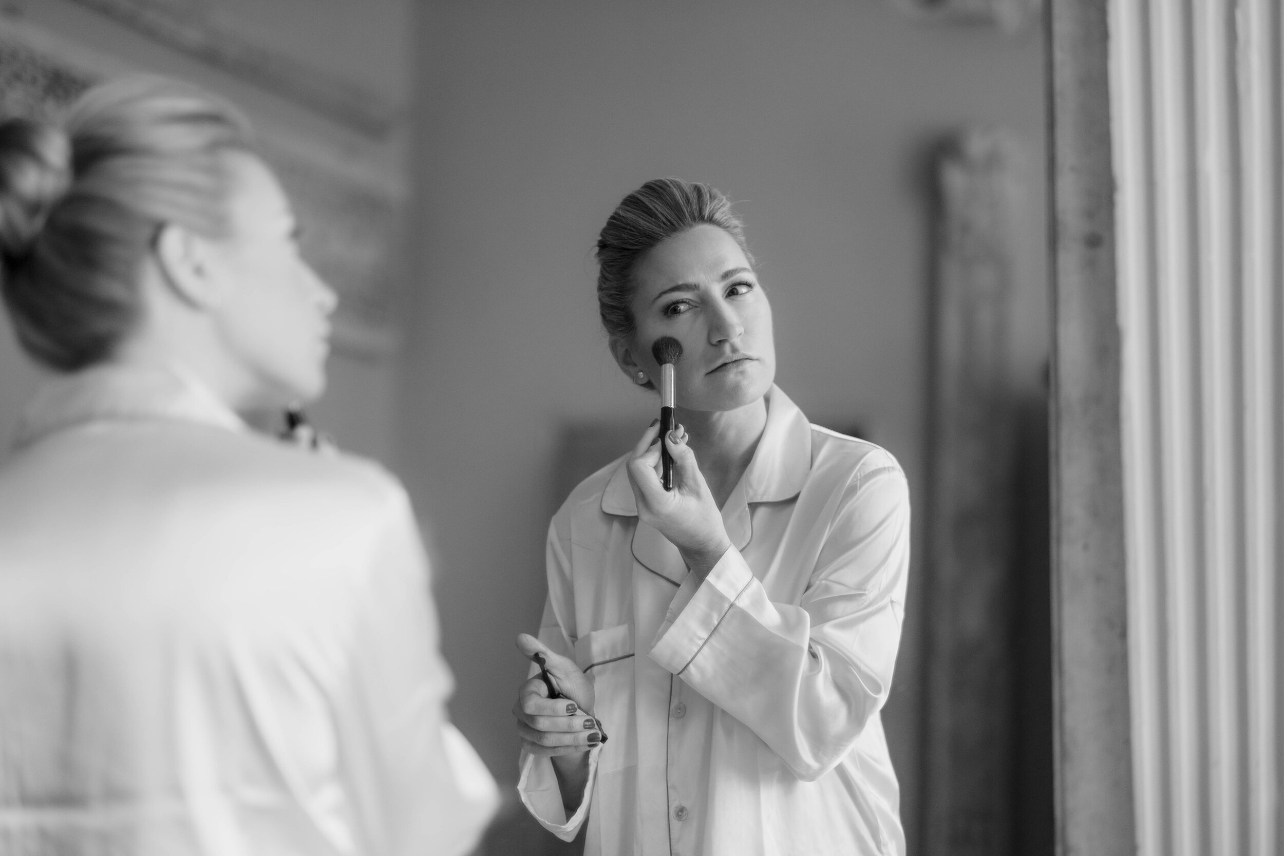 bride in mirror applying her make up