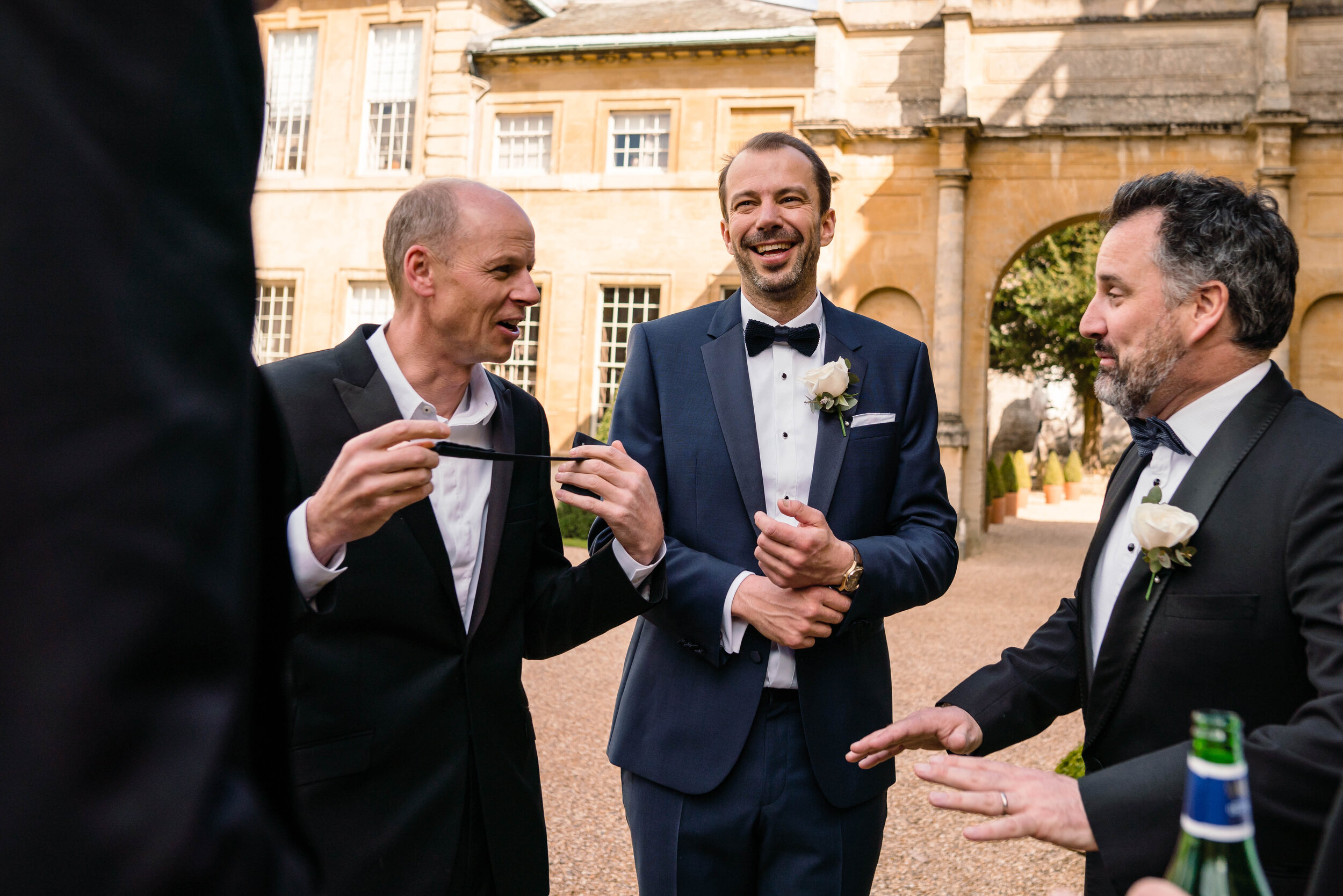 groom and friends laughing outside wedding venue