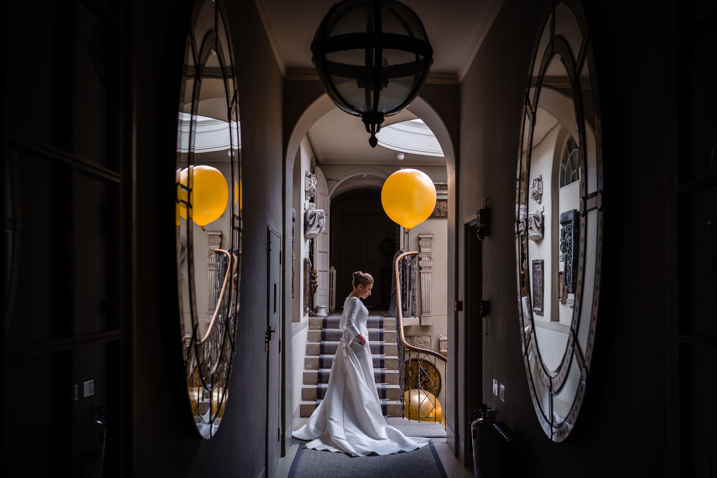 bride standing in corridor with yellow balloons and mirrors