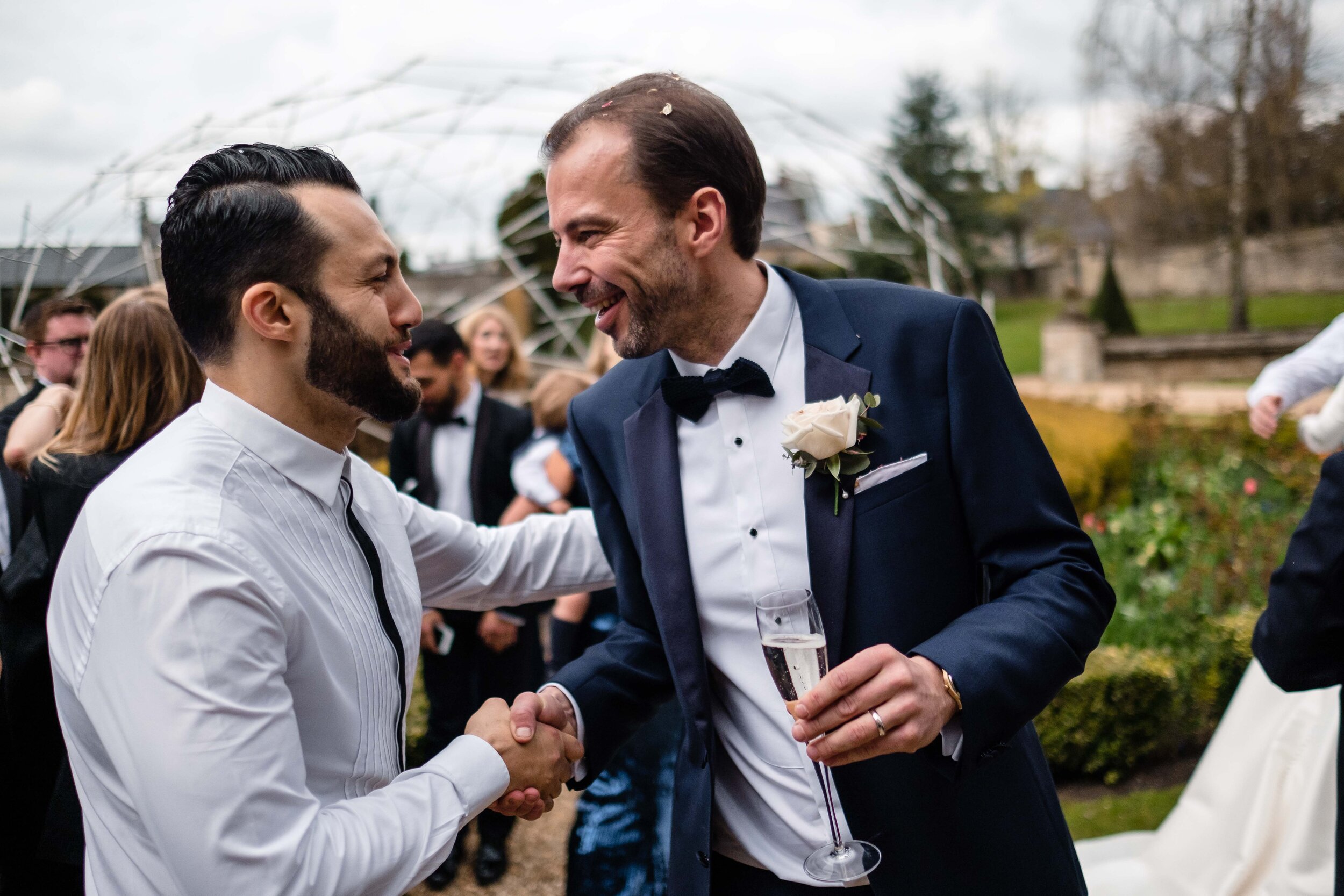 groom greeting friend with a handshake in a garden
