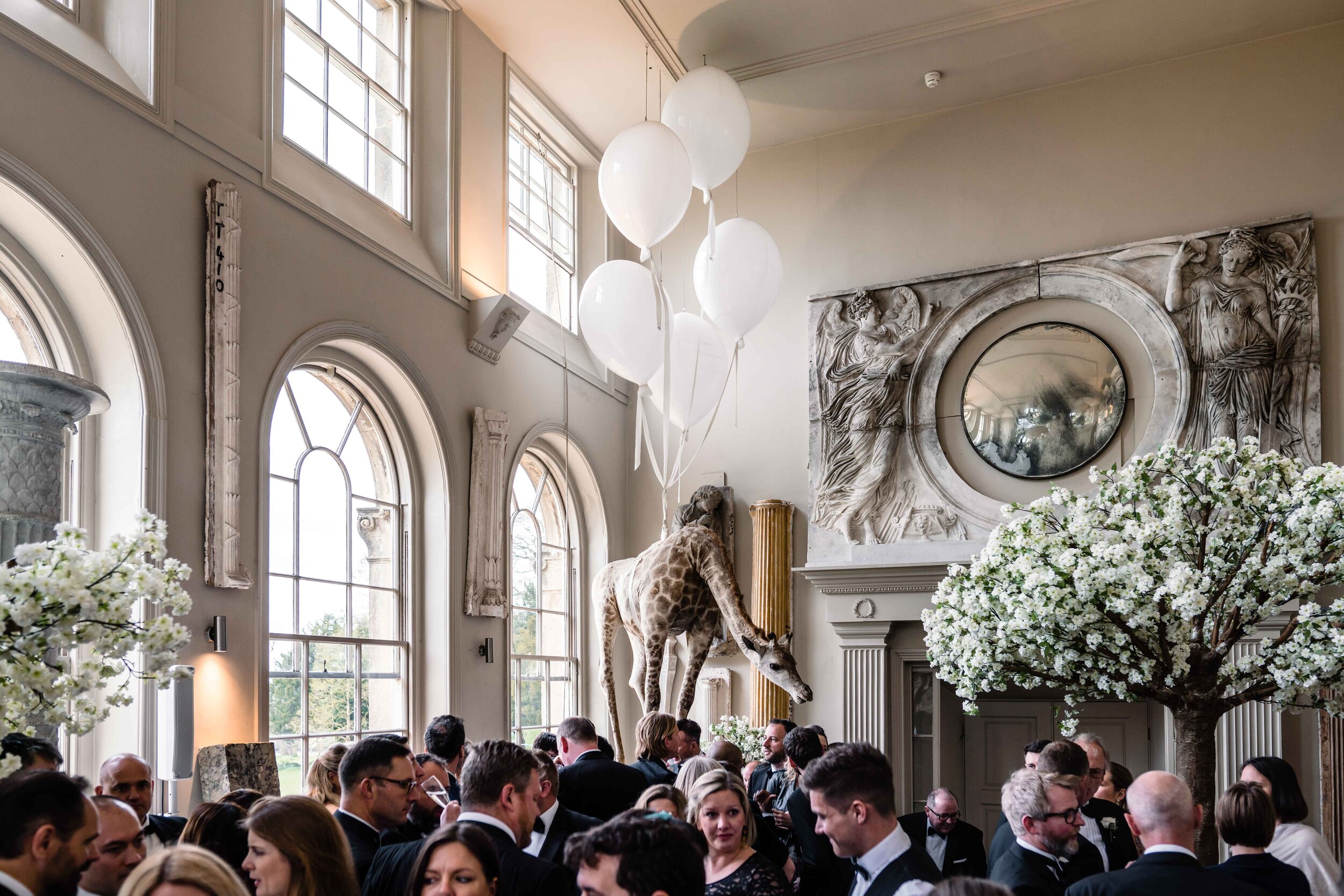 light filled orangery with a crowd of wedding guests with balloon decorations