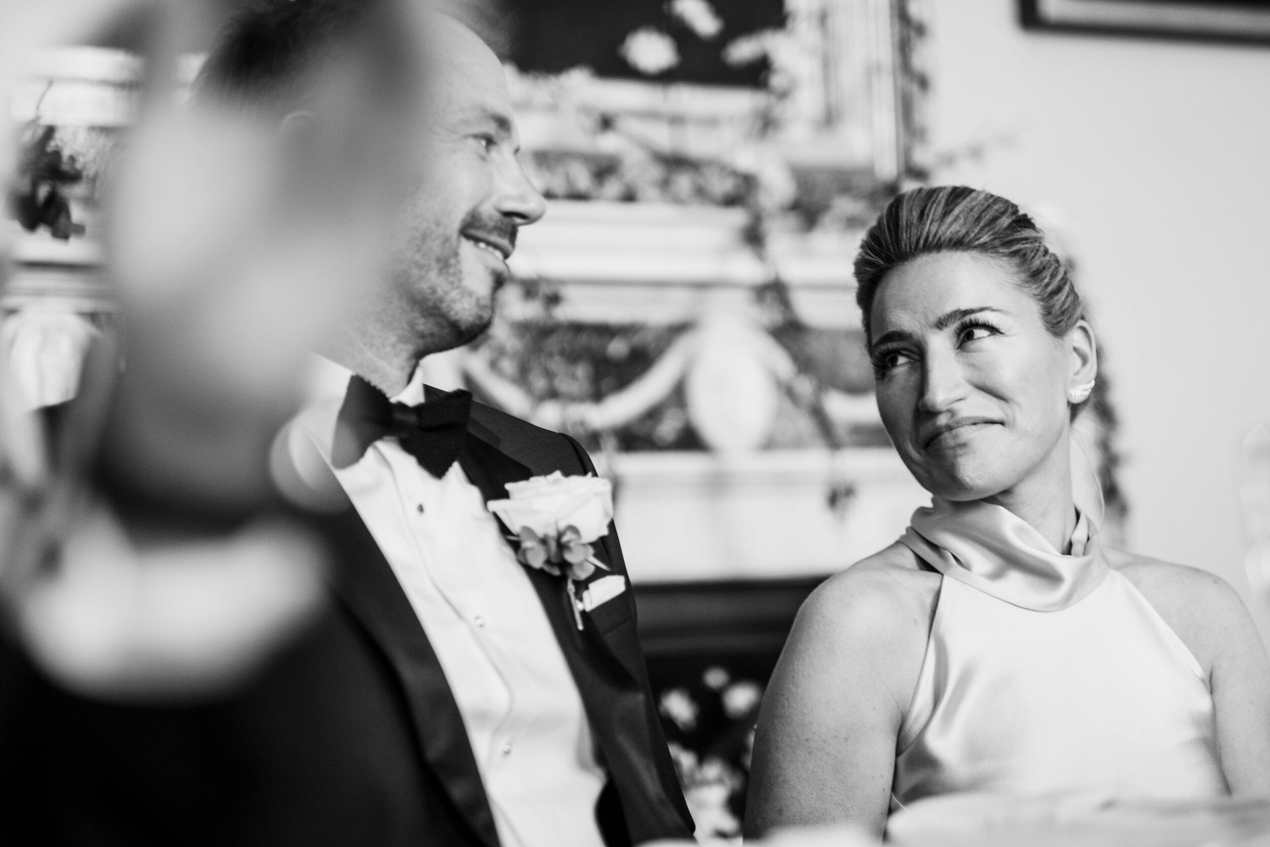 black and white bride looking at groom whose face is obscured with clapping hand