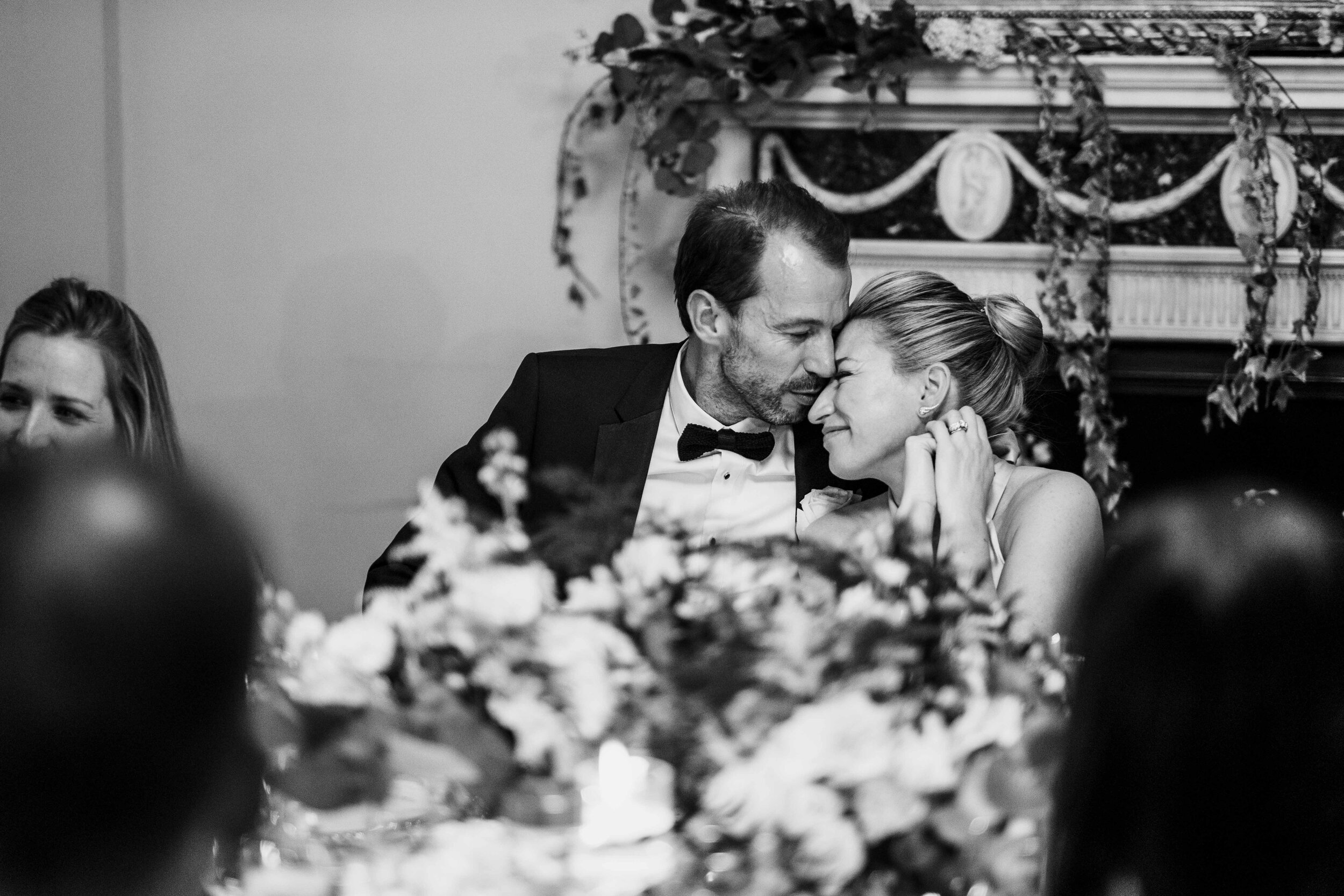 groom kissing the brides head whilst sat at the table