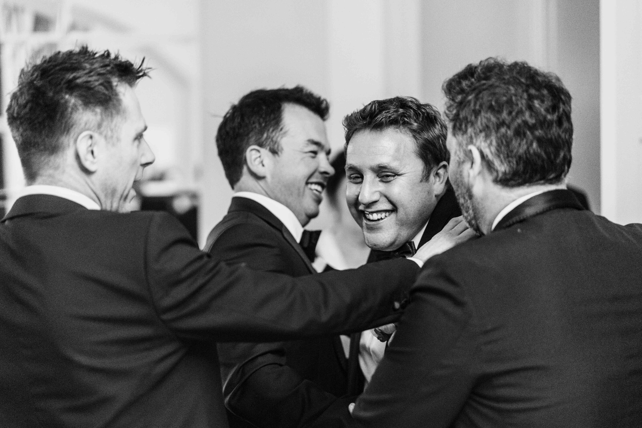 four men hugging and smiling black and white head and shoulders