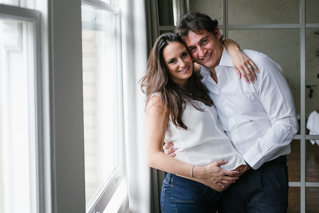 smiling couple pregnant woman top half standing by window