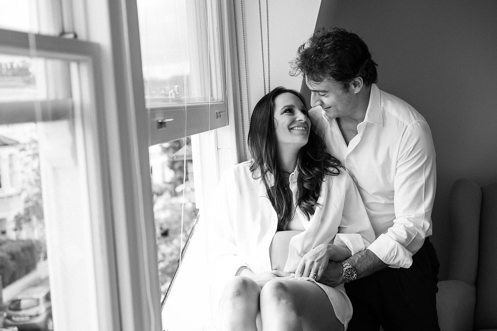 woman sitting in window frame next to man holding her both wearing white shirts