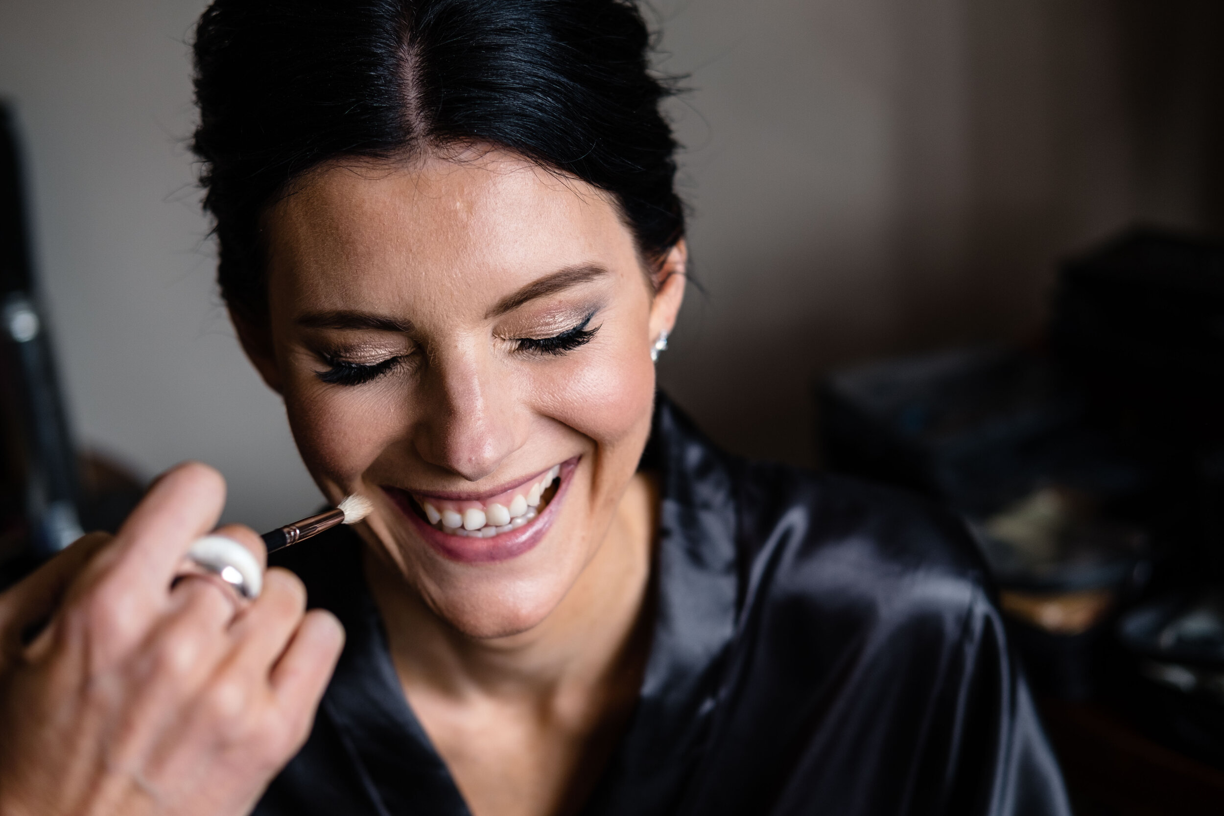 black haired girl laughing as make up applied