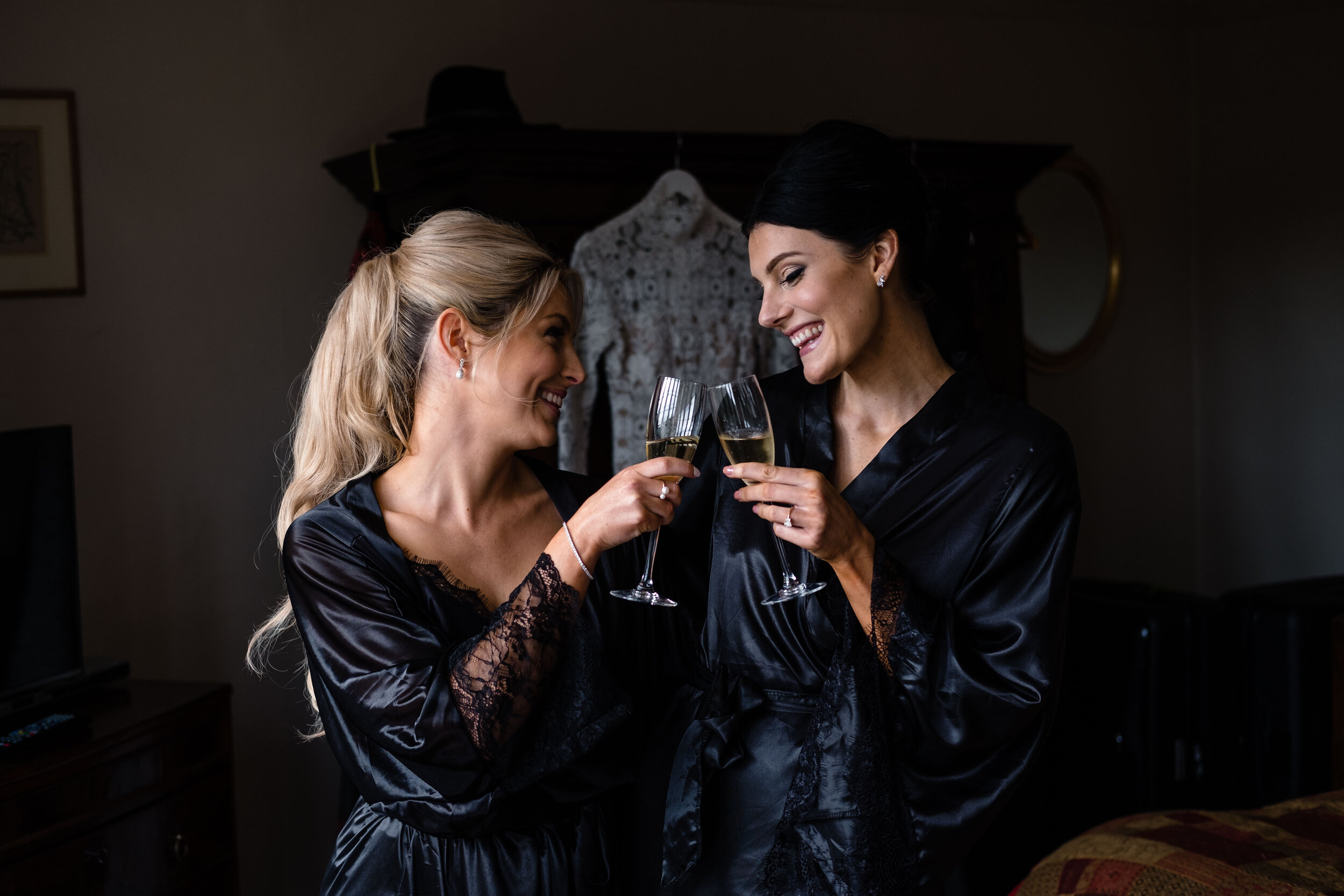 two women wearing black night gowns toasting champagne