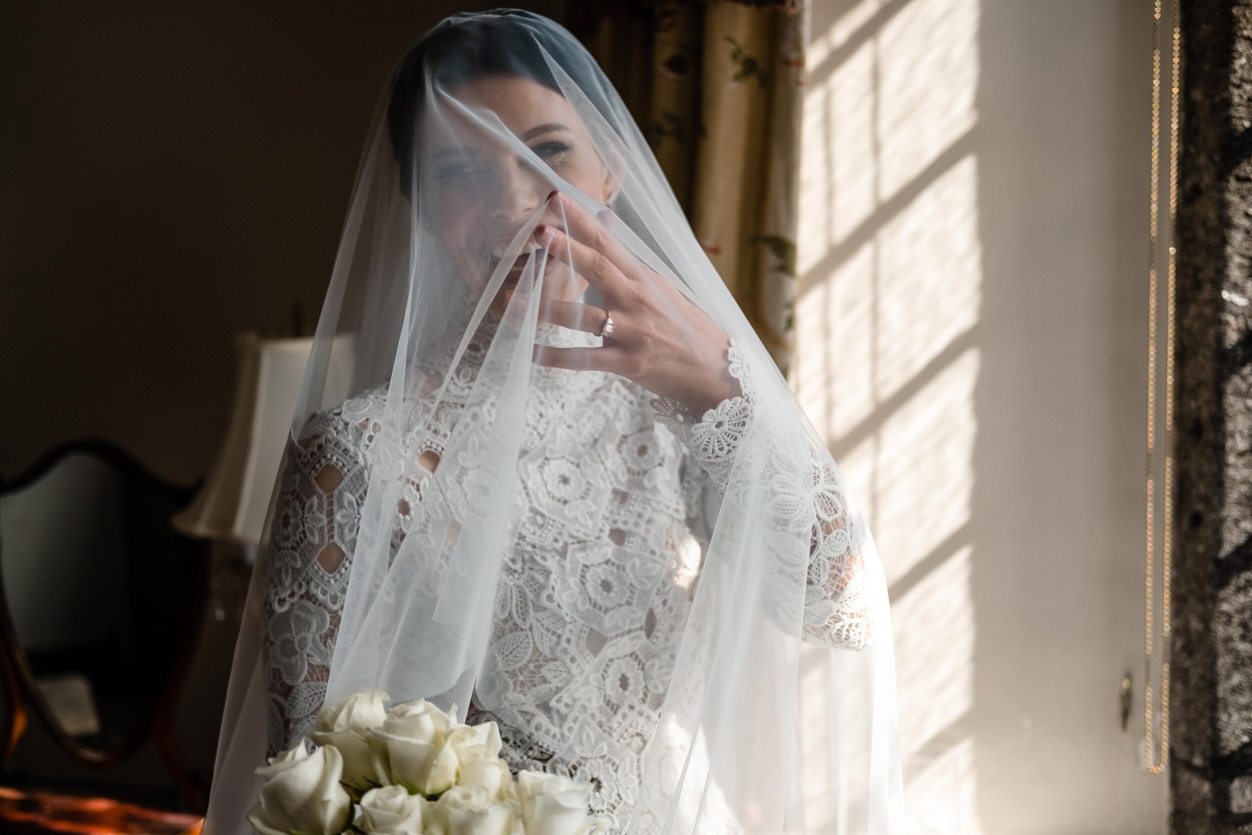 bride with veil over her face with window light