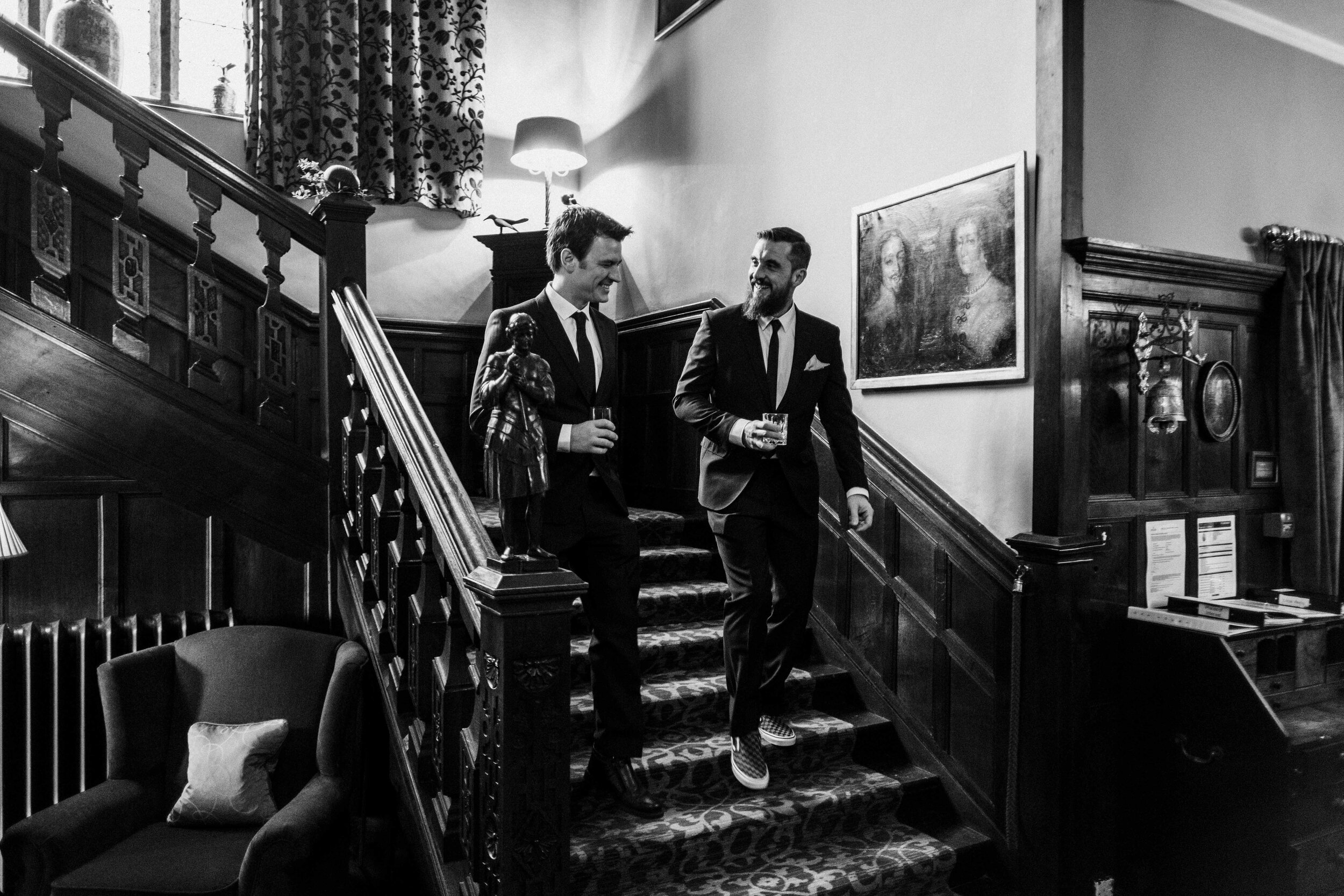 black and white photo of two men walking down grand stair case at Lewtrenchard Manor