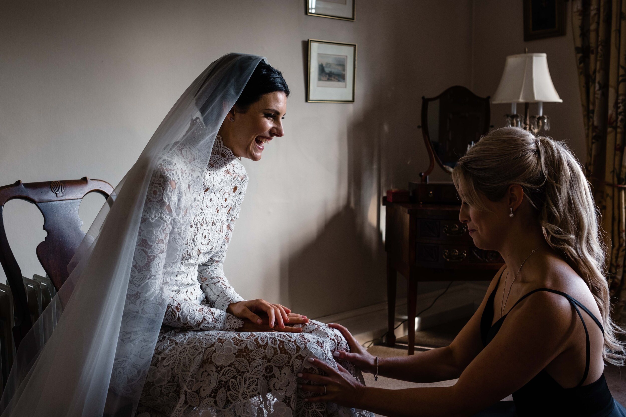 bride sitting and bridesmaid sitting holding her knees