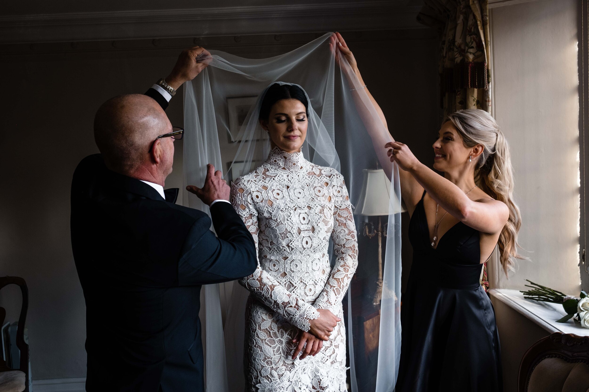 father and friend putting veil over brides face