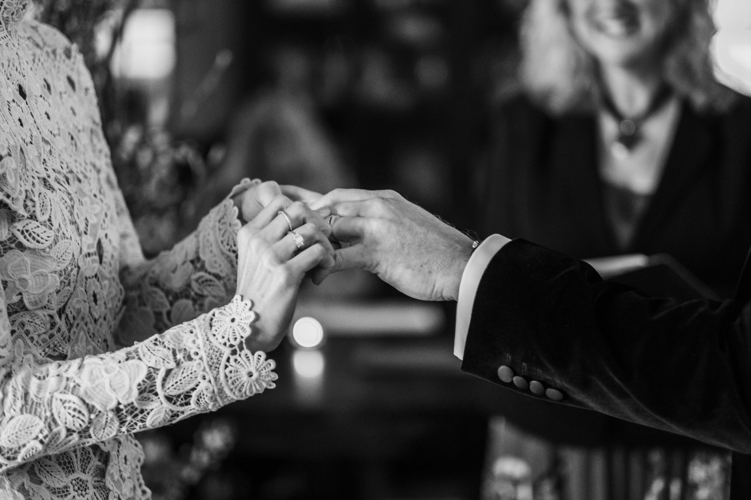 close up black and white bride and groom hands putting on wedding ring