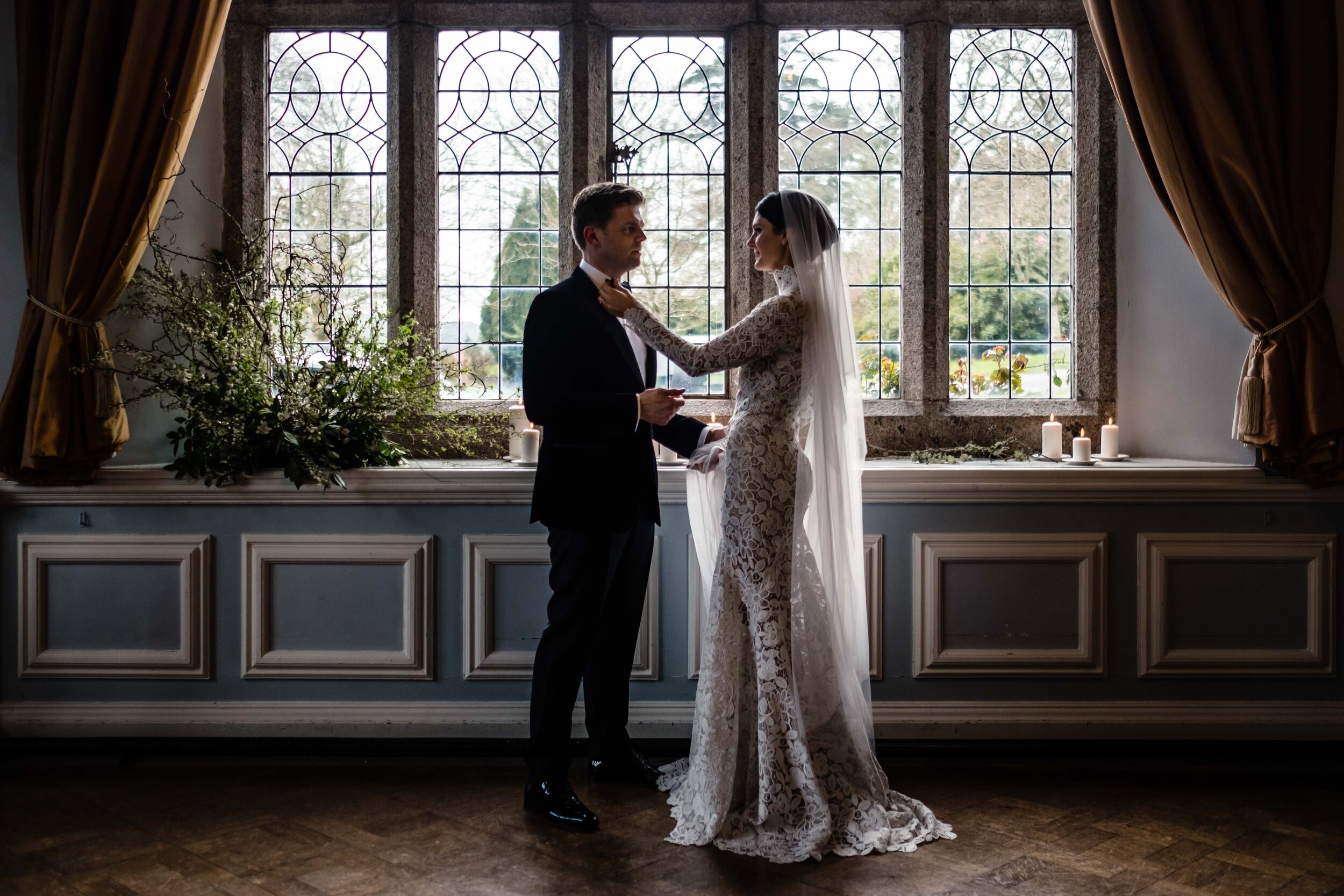 bride and groom in front of big window in ballroom at Lewtrenchard Manor