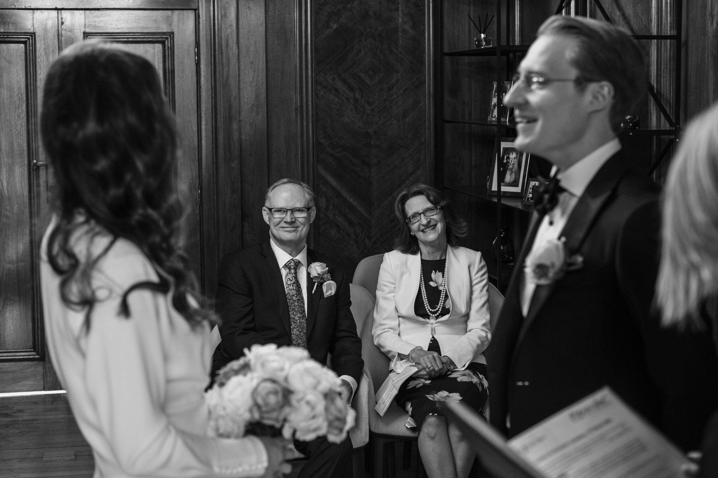 mother and father framed by bride and groom during wedding vows