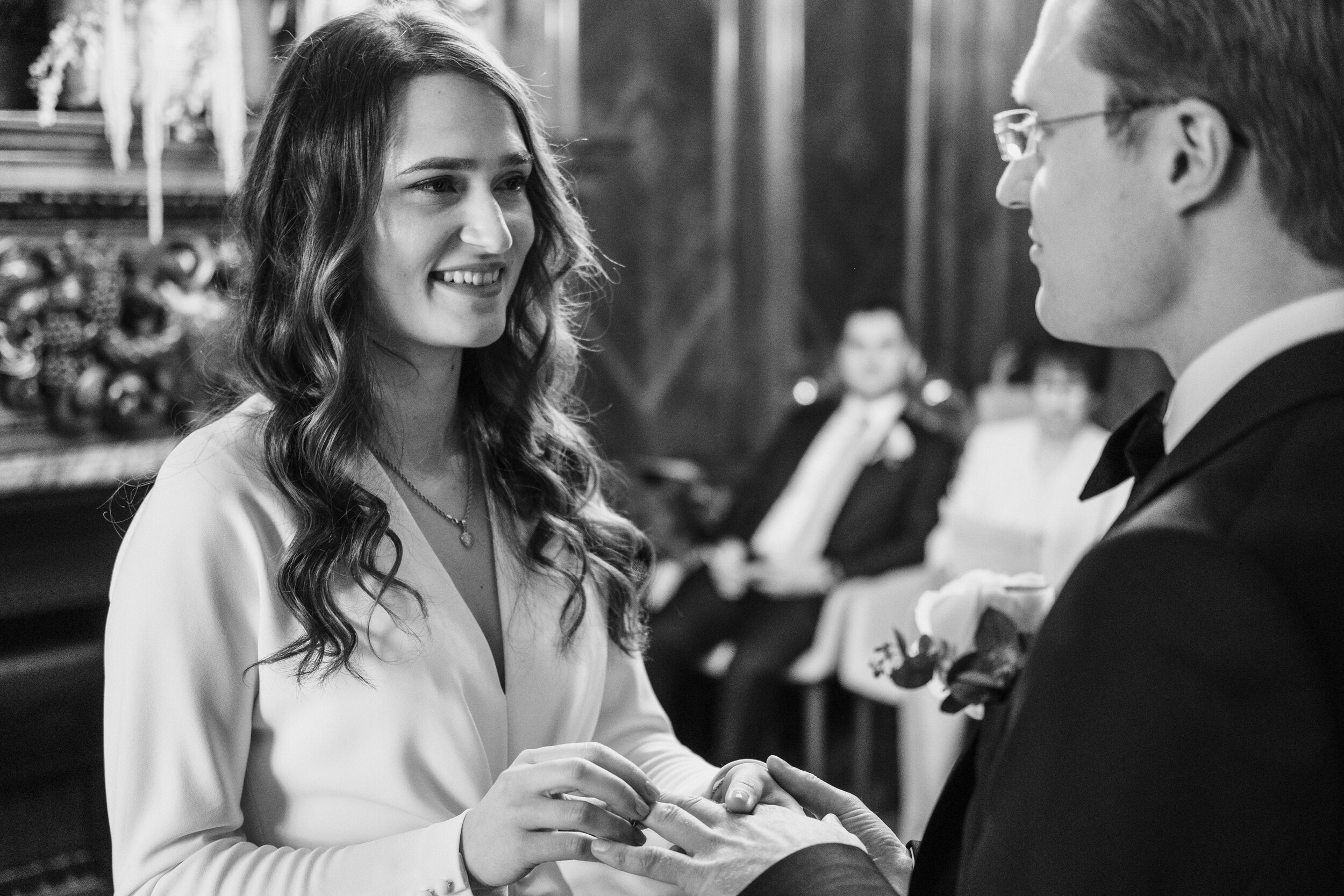 bride smiling at groom during wedding ceremony as she puts on his ring
