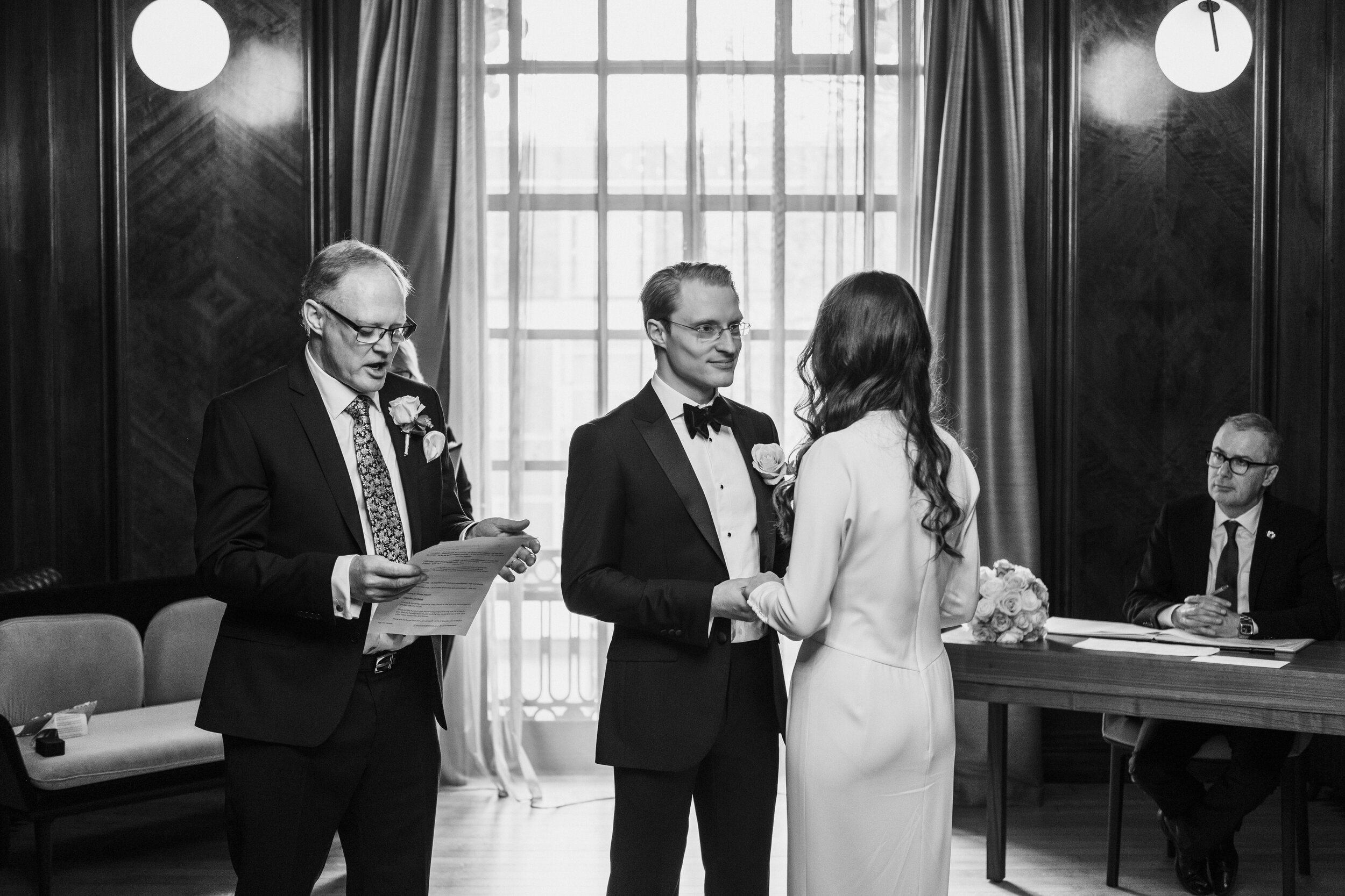 father reading speech to bride and groom in light filled ceremony room