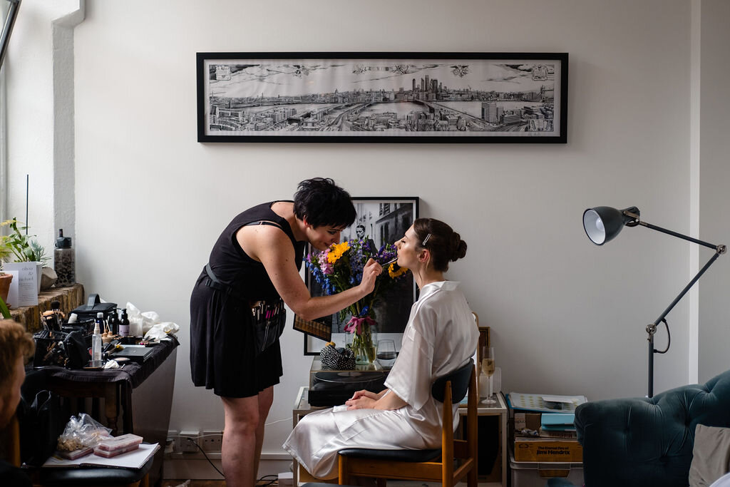bride having her make up done in flat with picture of London on the wall