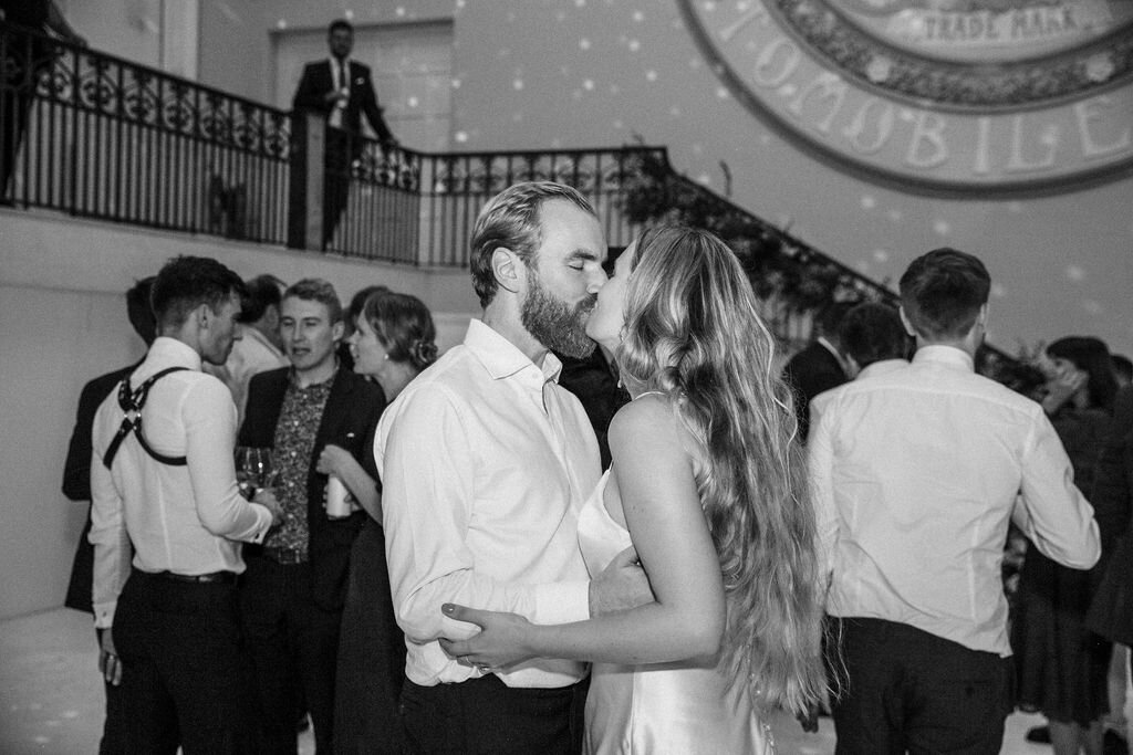 black and white of bride and groom kissing on dance floor
