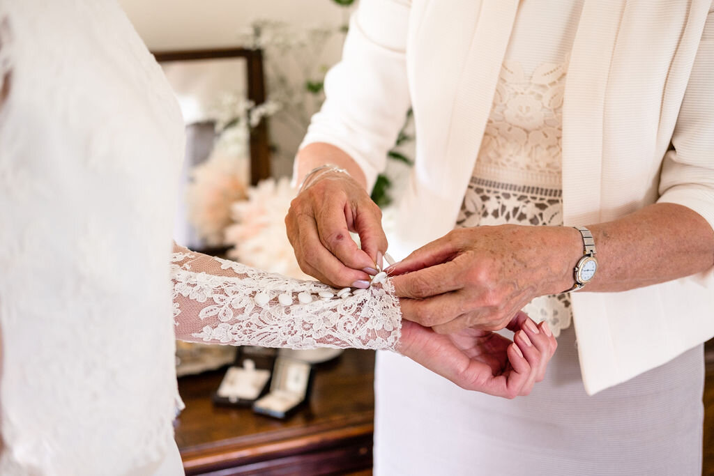 close up of mother doing up brides cuff on wedding dress