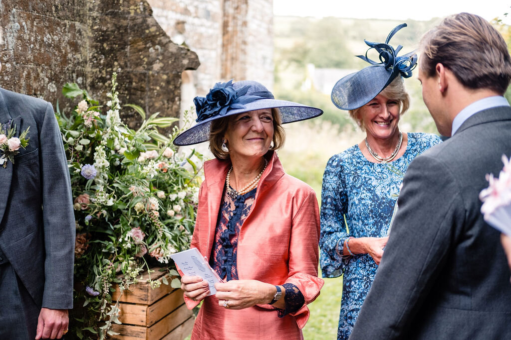 two women greeting groom in blue hats and pink outfit