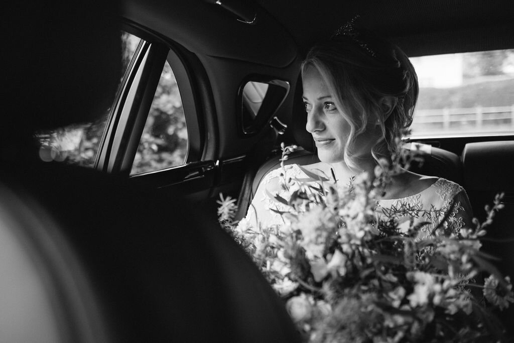 black and white beautiful bride with bouquet in back of car
