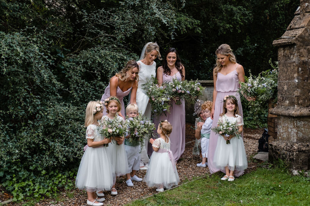 bridesmaids and flower girls standing with bride
