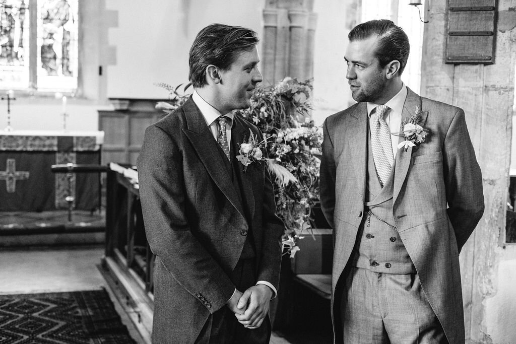 groom and best man black and white standing at alter in church