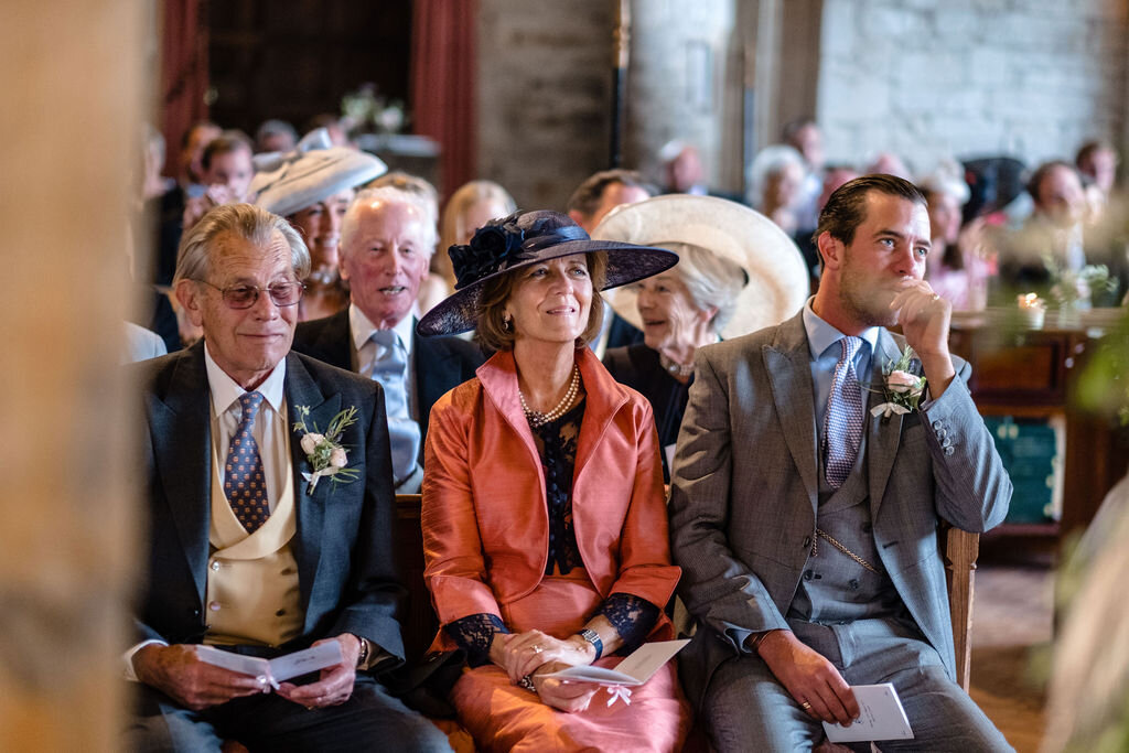 three wedding guests sitting in church woman wearing pink