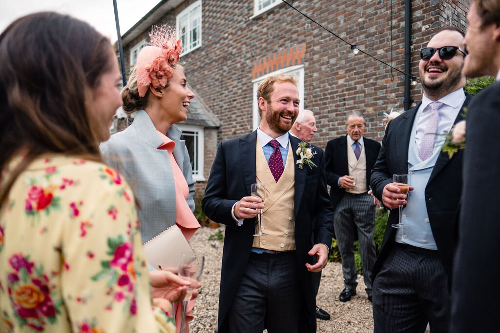 wedding guests laughing in front of house
