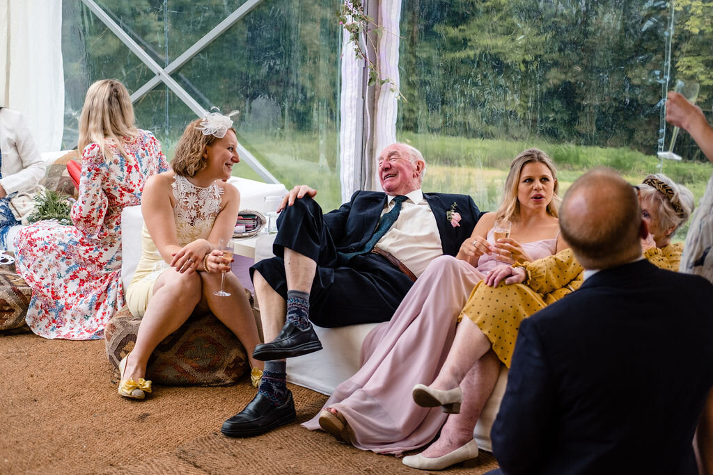 wedding guests sitting on sofas laughing