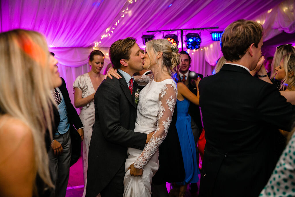 dance floor party wedding guests bride and groom kissing