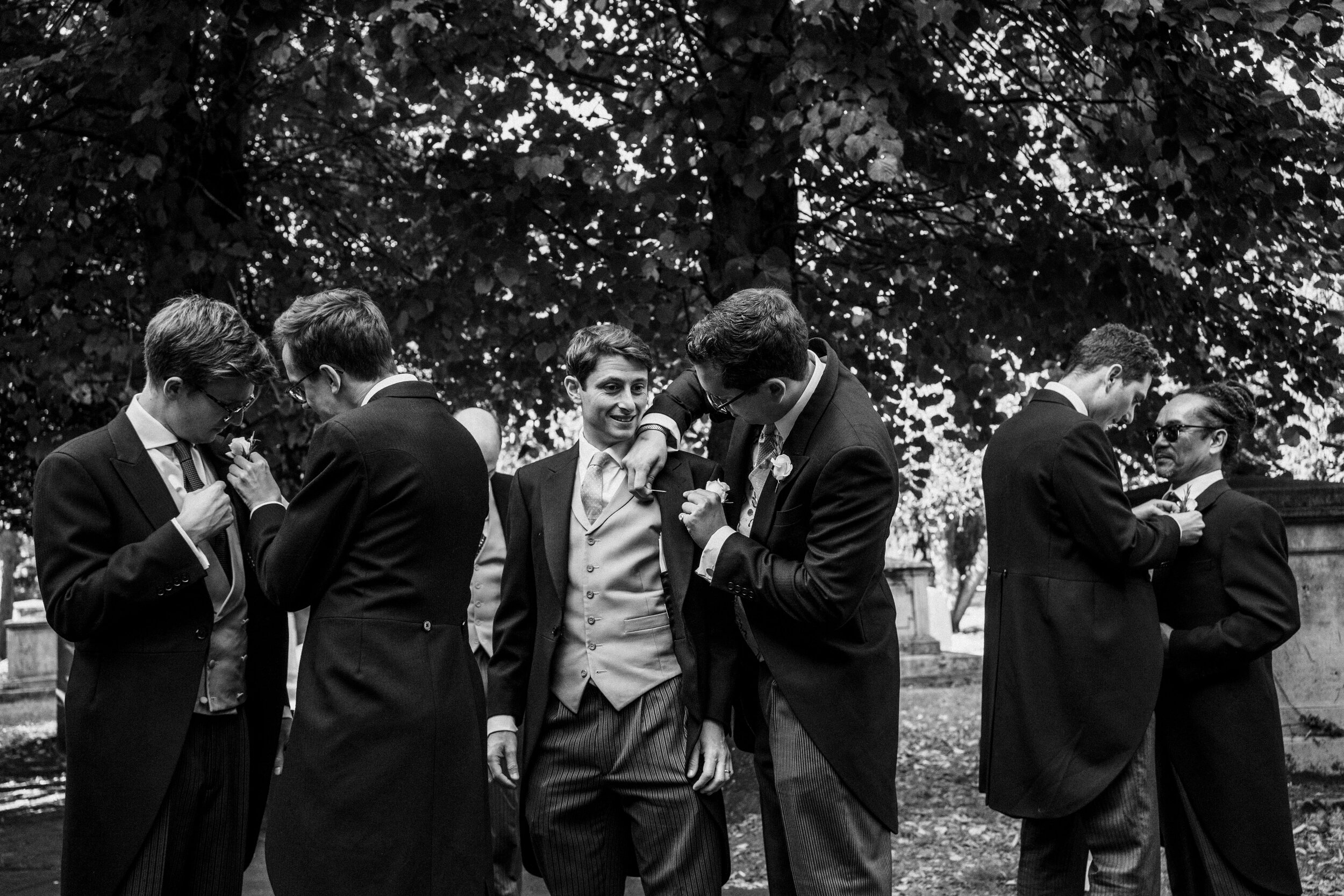 groom and ushers outside church in Fulham black and white