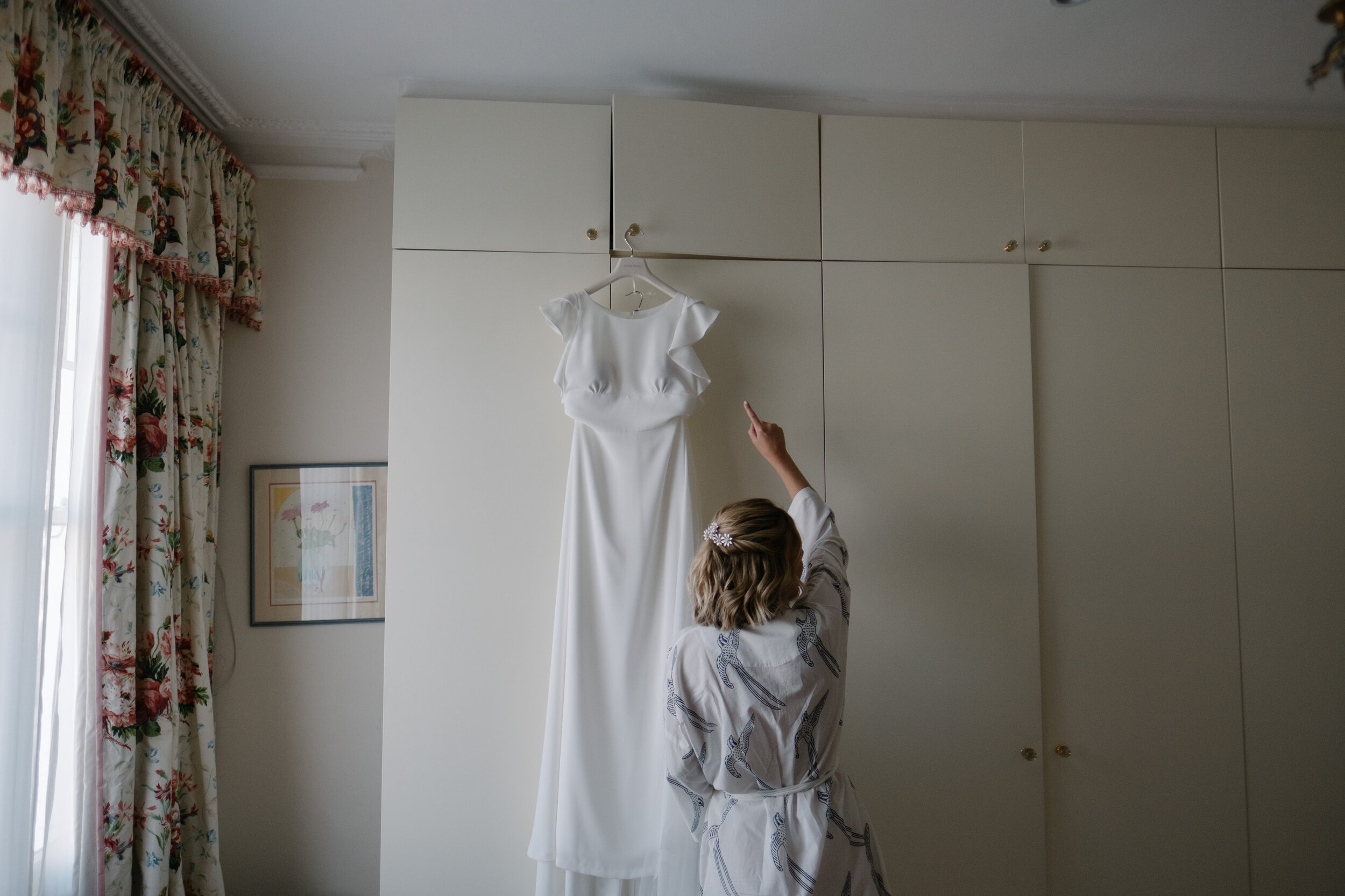 bride reaching for gown in home