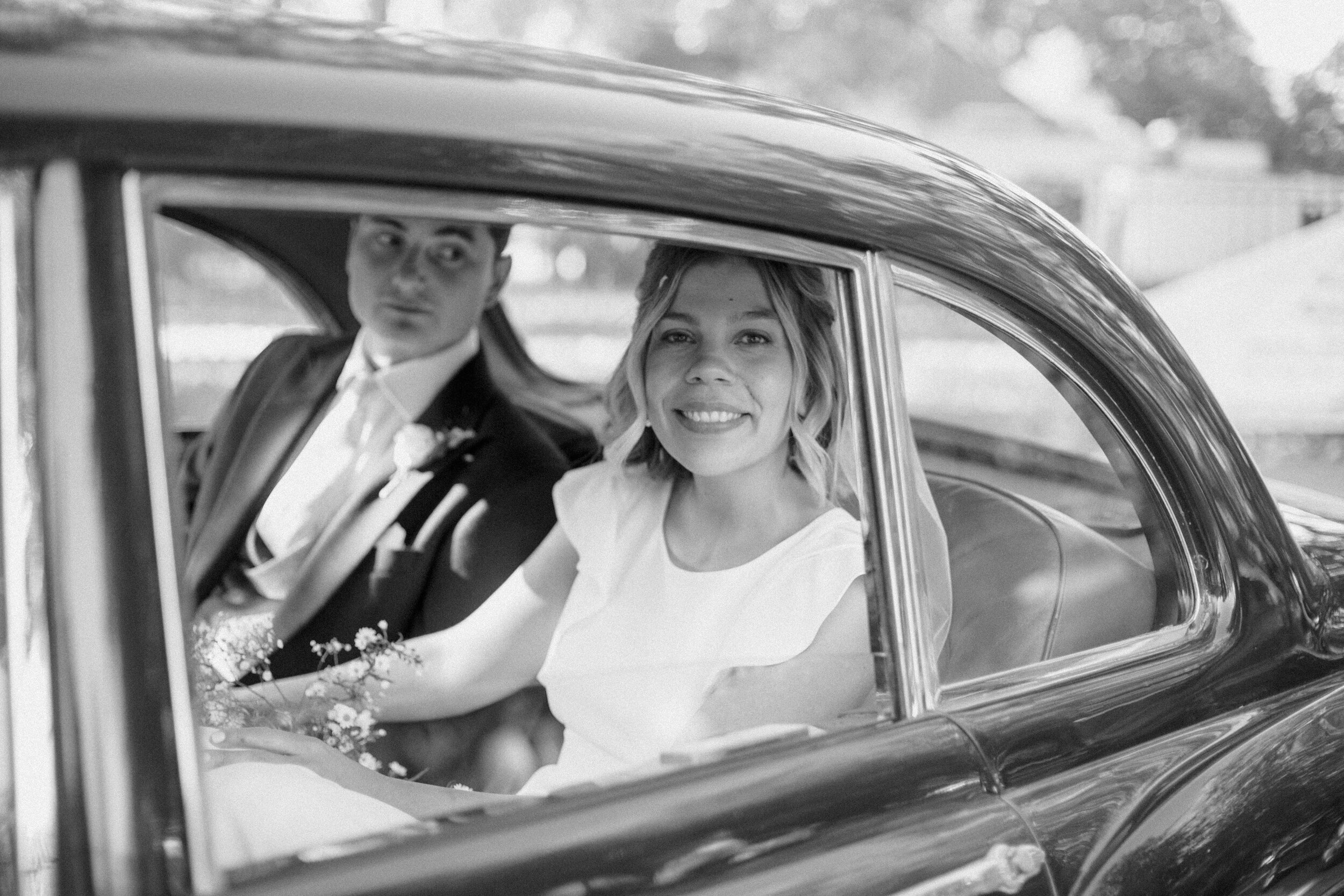 black and white through car window of smiling bride