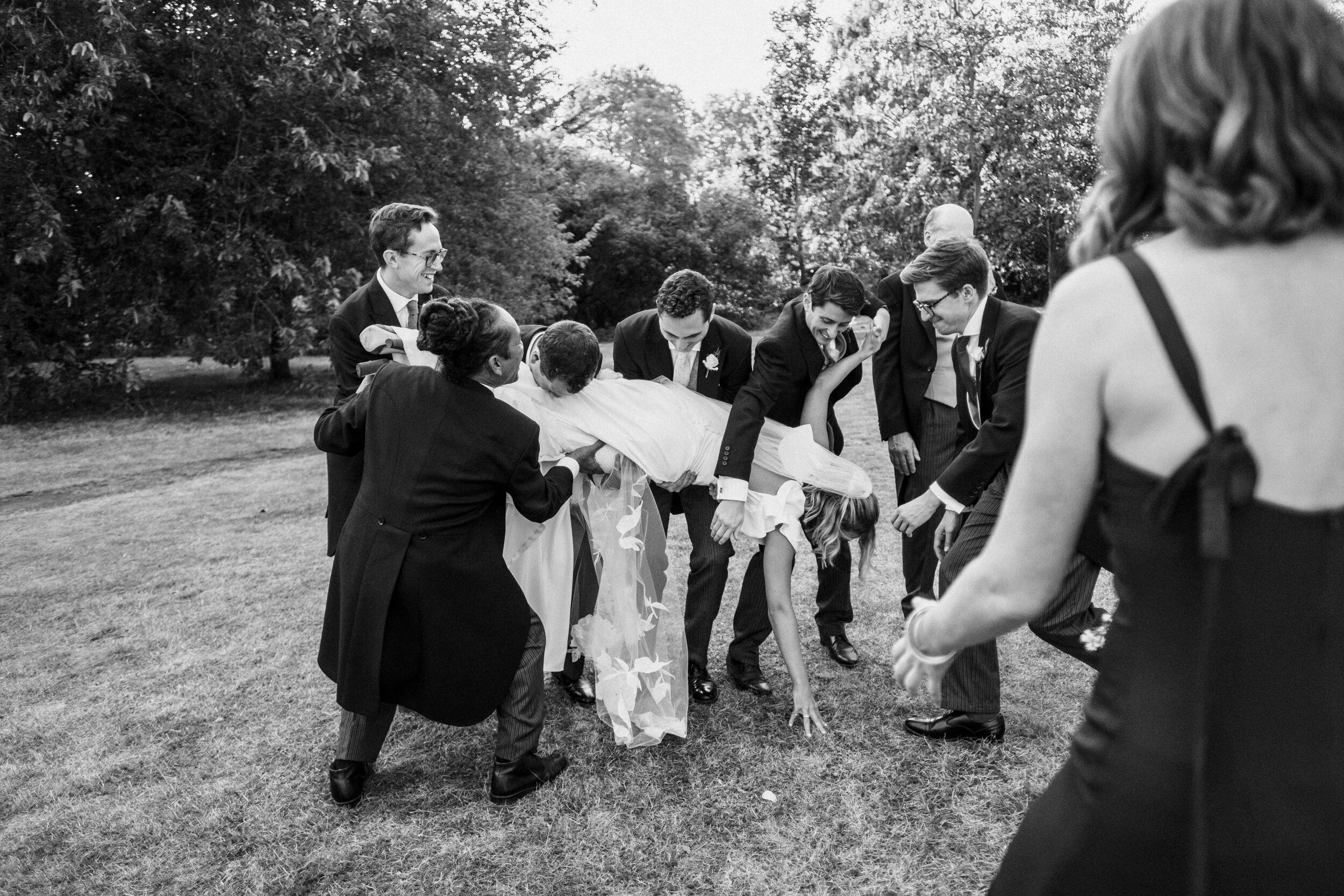 ushers dropping bride during family photos at wedding at Fulham Palace