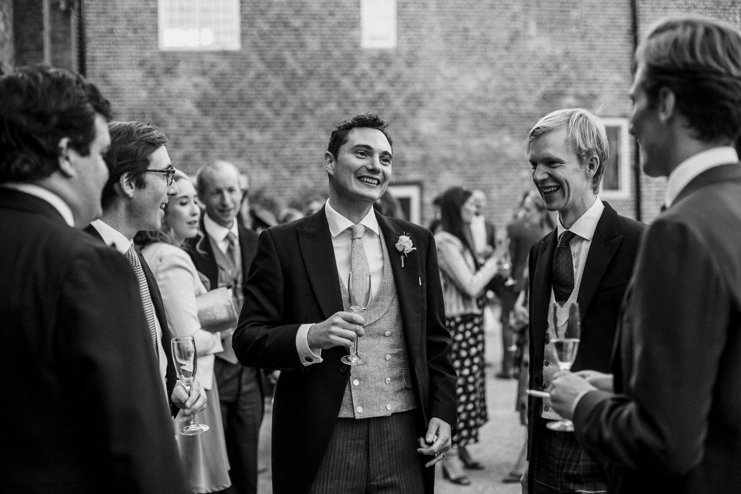 groom surrounded by friends at wedding black and white photo