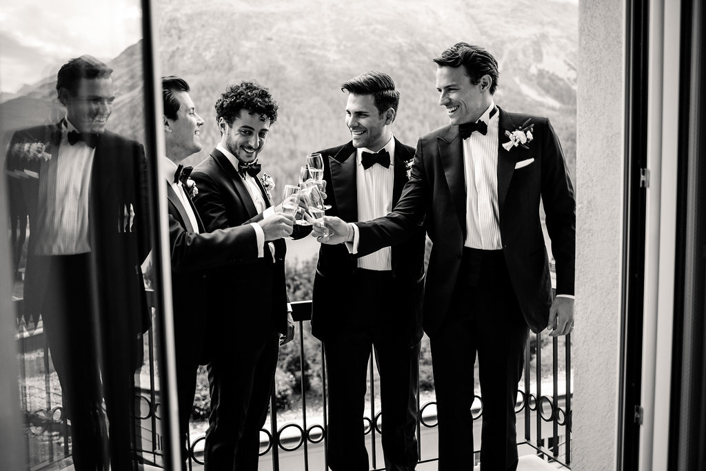 black and white groom and ushers on balcony toasting